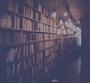 Cozy library interior with bookshelves and warm hanging lights creating a serene atmosphere.